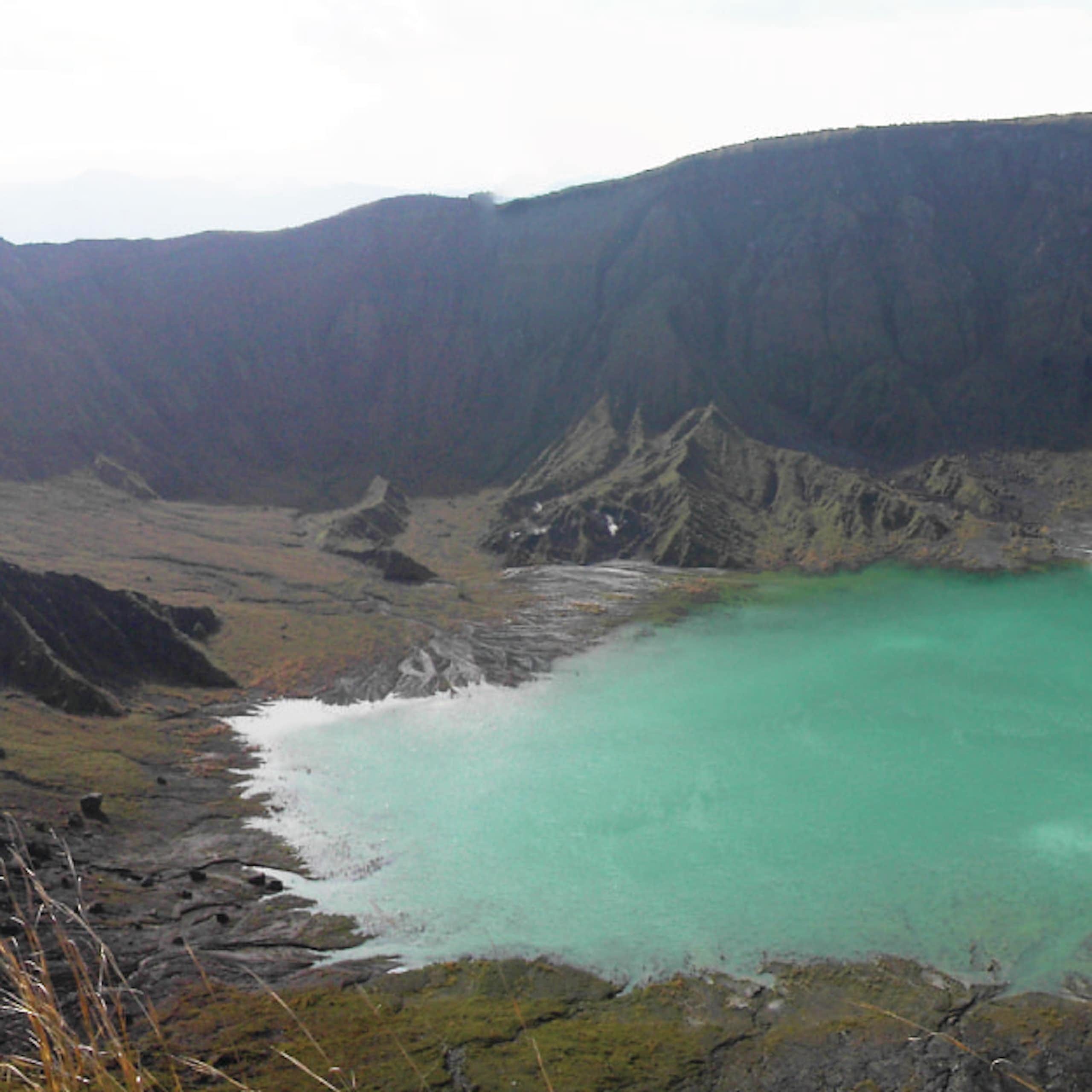 vulcão, lago azul no topo da montanha, céu cinzento