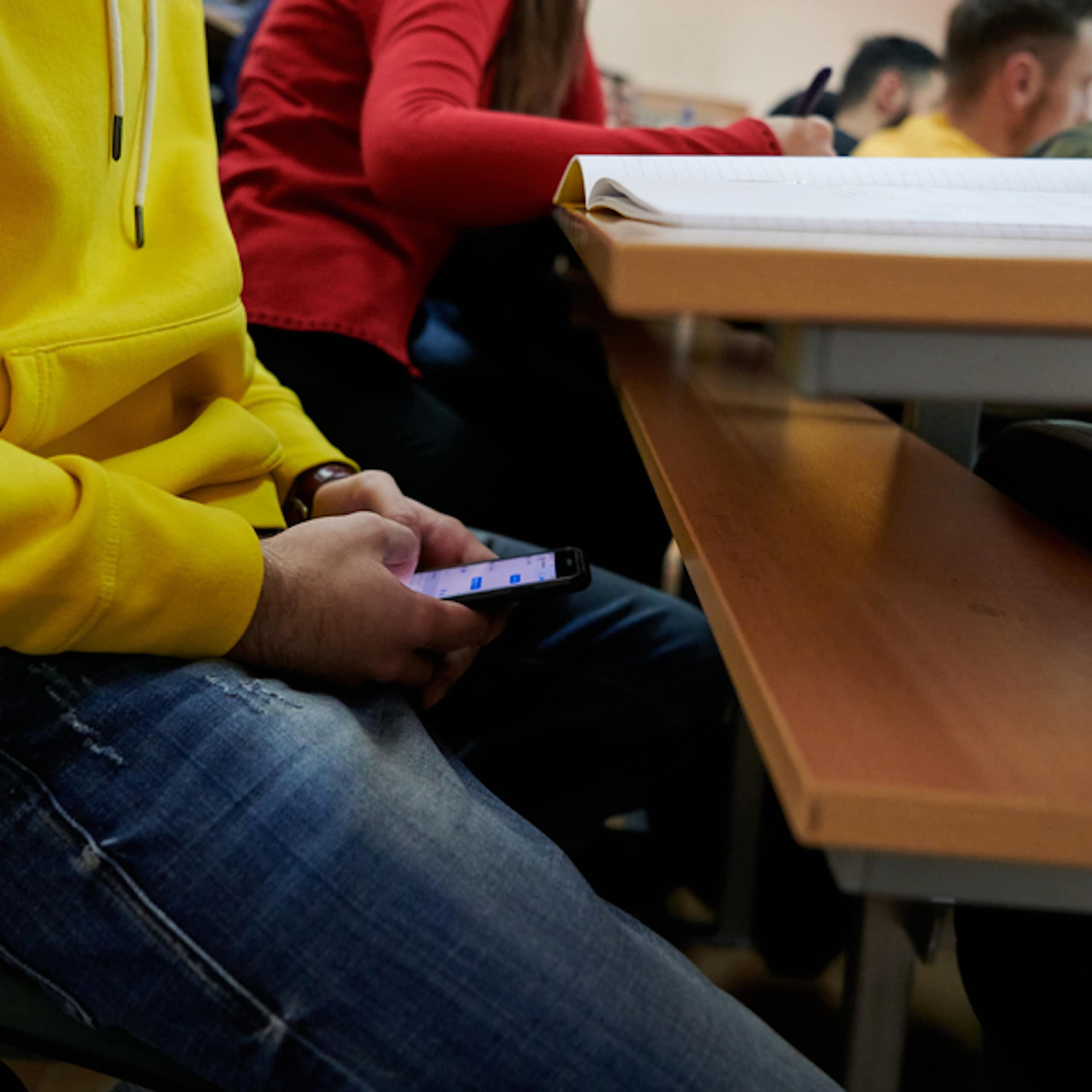 Un amphithéâtre où un étudiant utilise ChatGPT sur son téléphone portable.