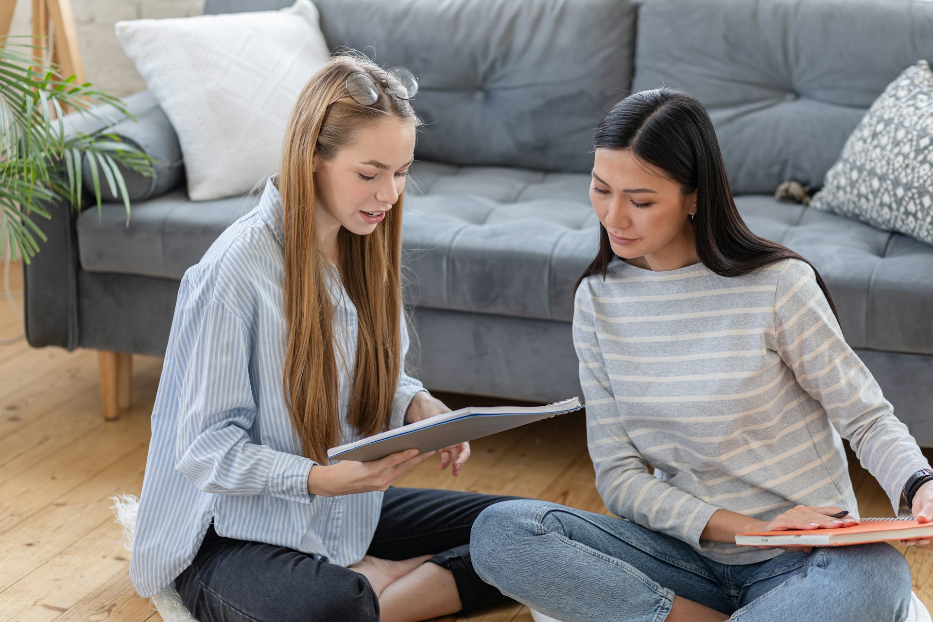 Women sat on floor looking at notebooks together