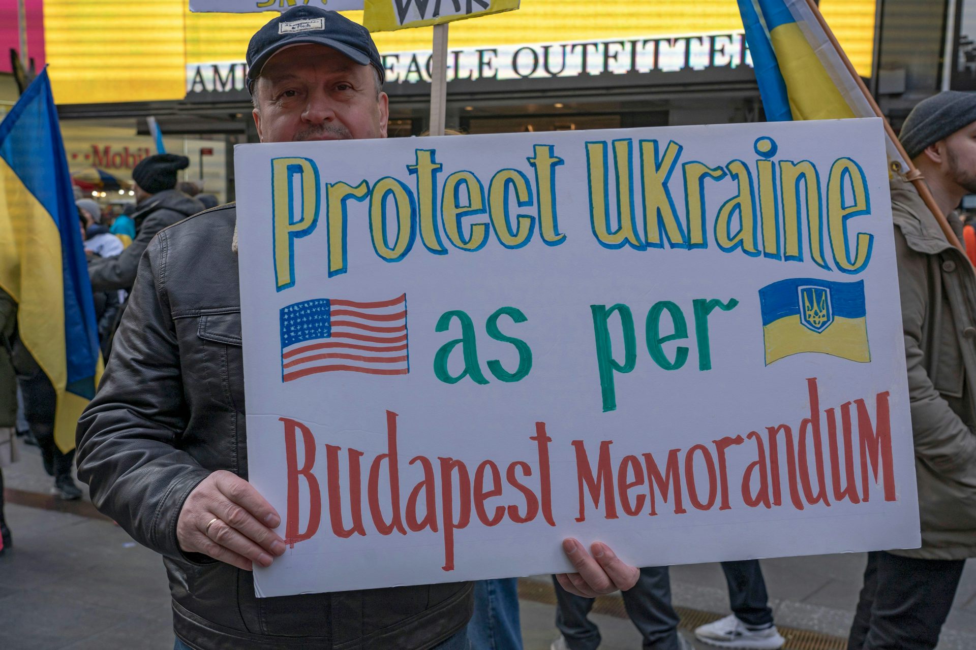 A supporter of Ukraine in New Yorkholds up a banner calling for the US to proect Ukraine as pder the Budapest Memorandum.