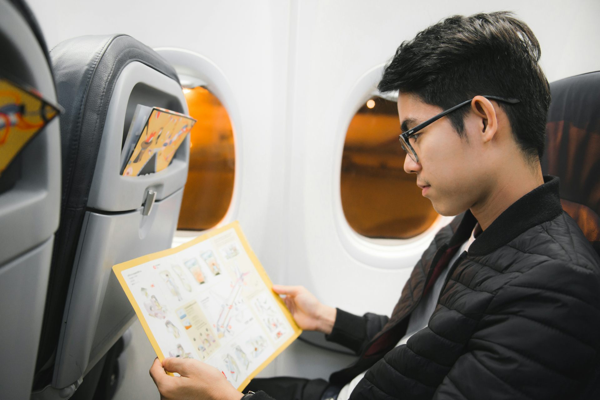 Un pasajero lee atentamente las instrucciones de evacuación en caso de emergencia aérea.