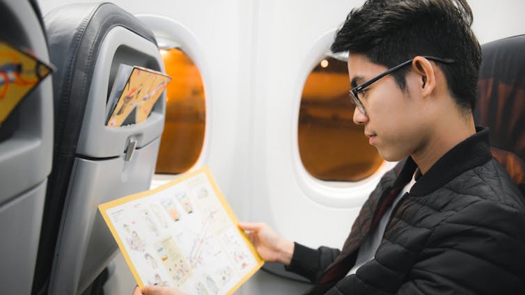 El pasajero lee atentamente las instrucciones de evacuación en caso de emergencia.