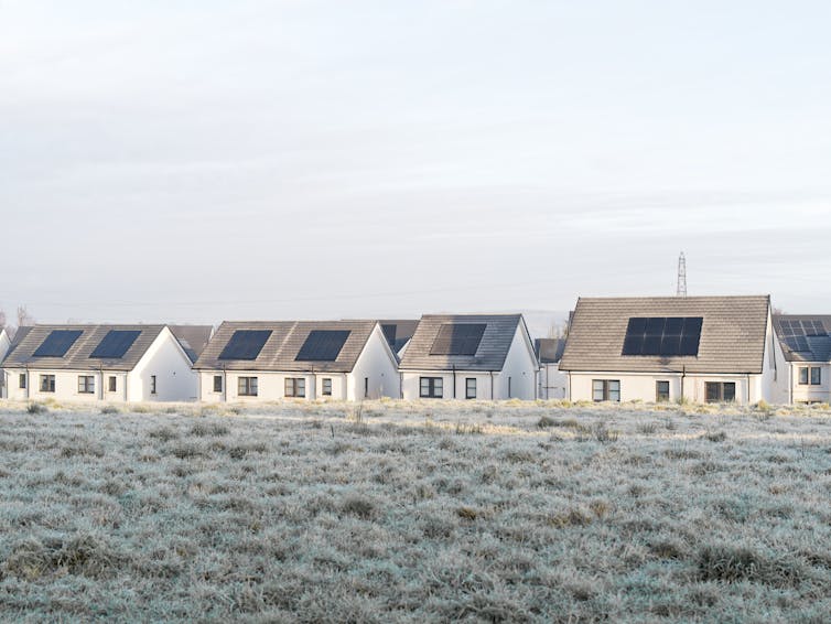Homes with solar panels on frosty day.