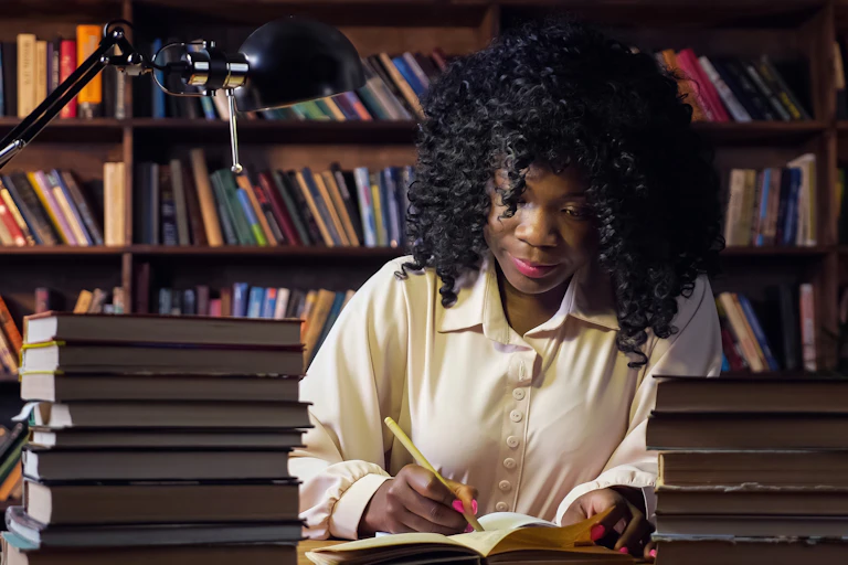 Black woman working at desk surrounded by books