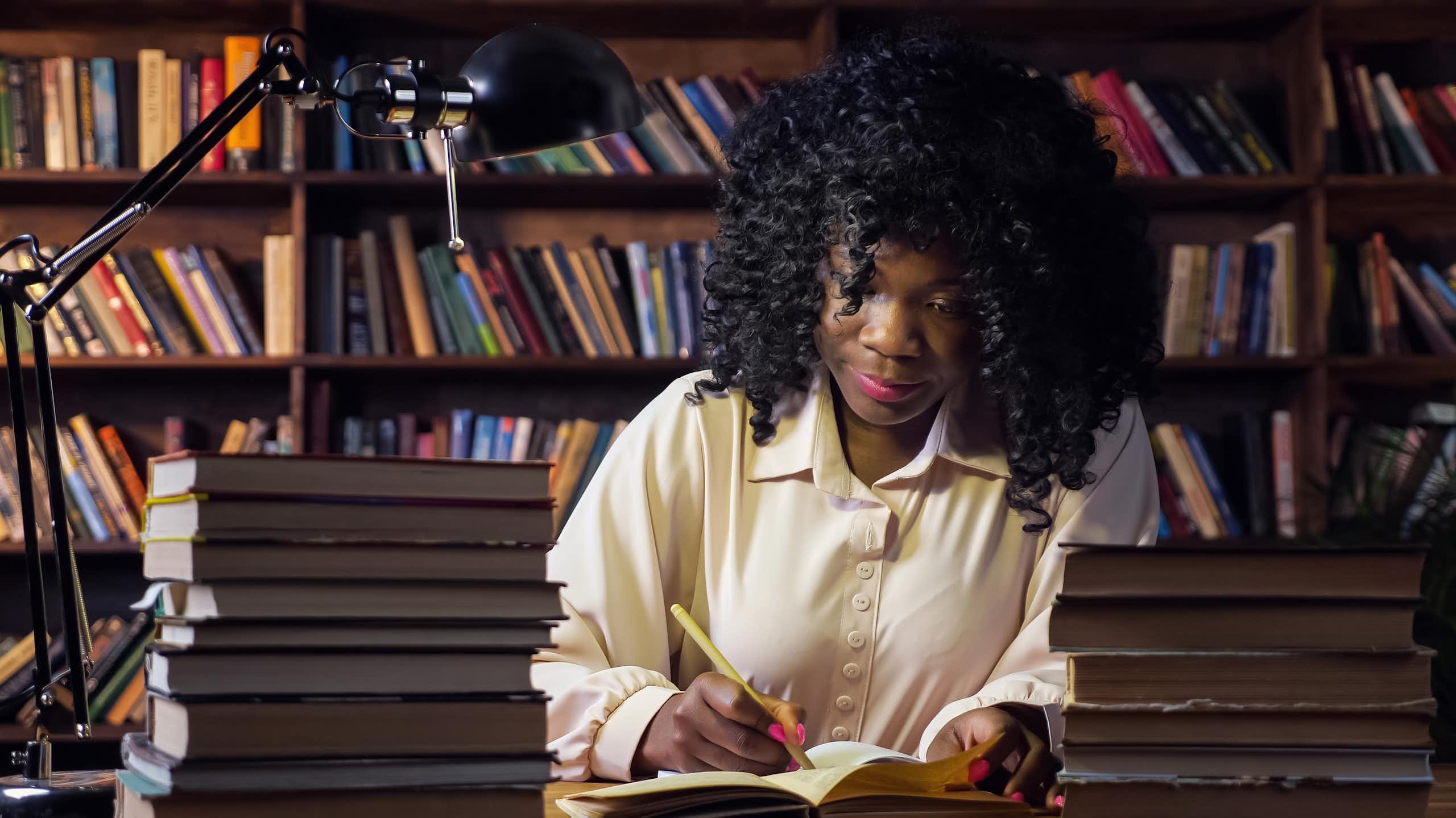 Black woman working at desk surrounded by books