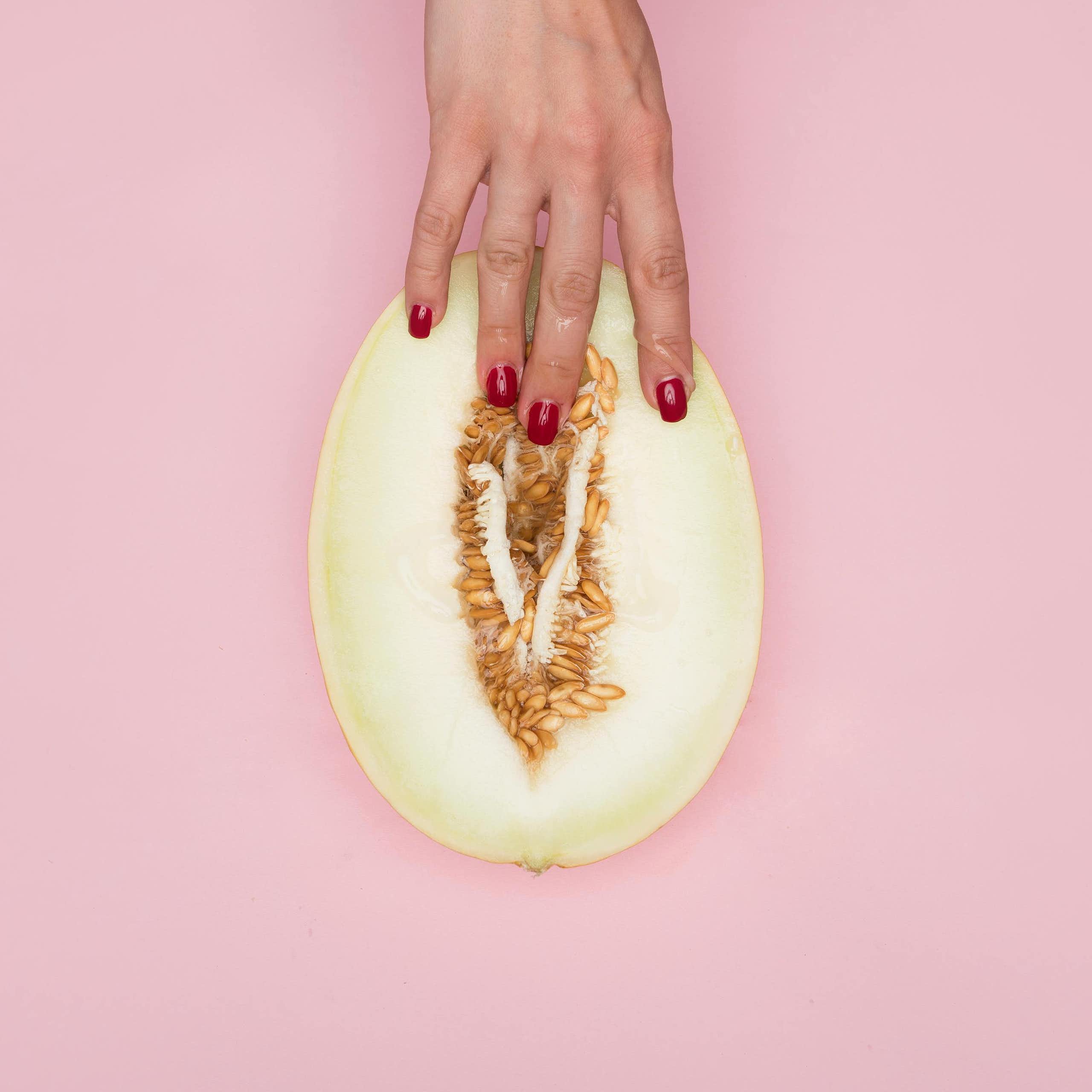 Main de femme tenant un melon, les doigts enfoncés dans la partie charnue.