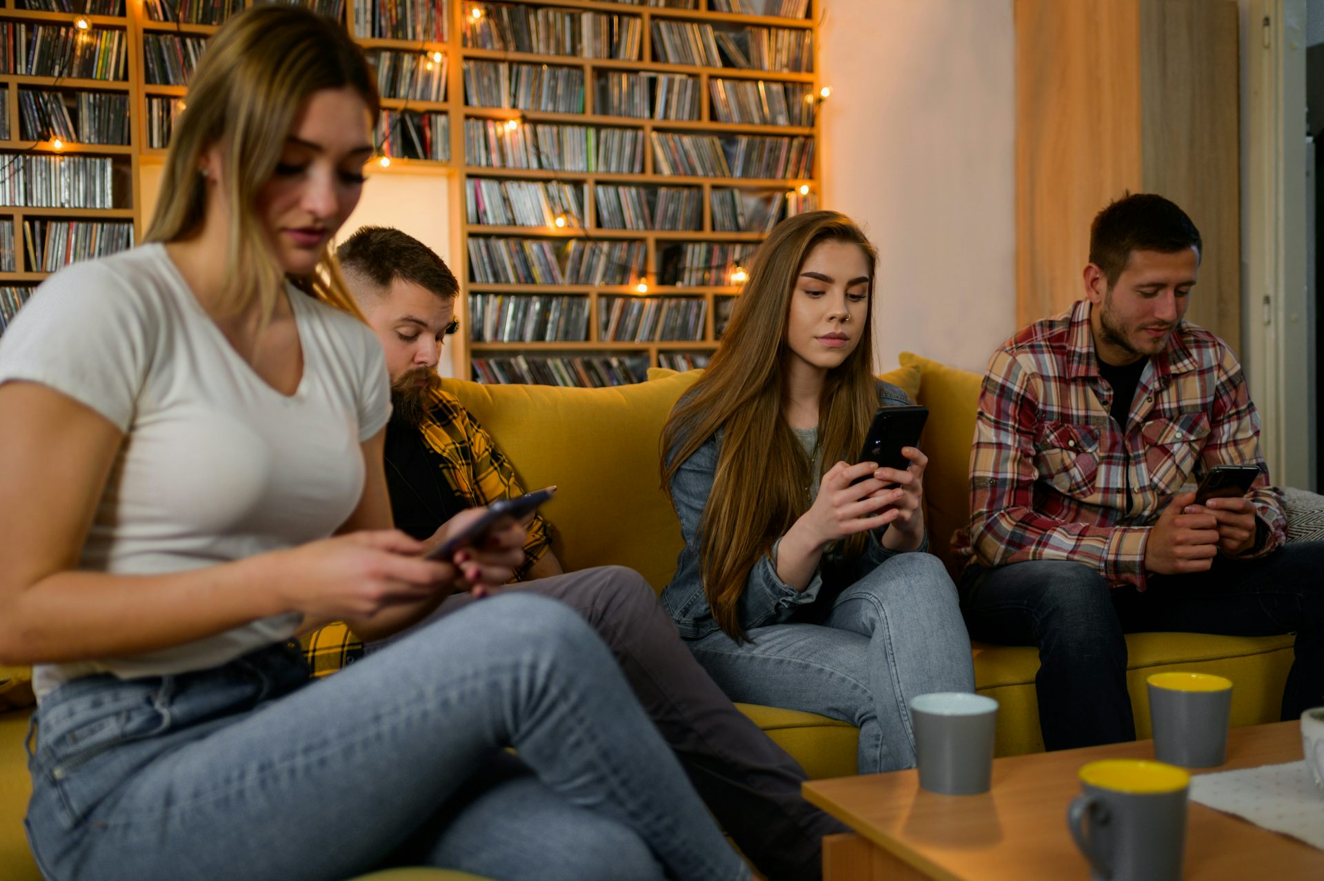 Les membres d’une famille installée dans son salon consultent leur appareil électronique