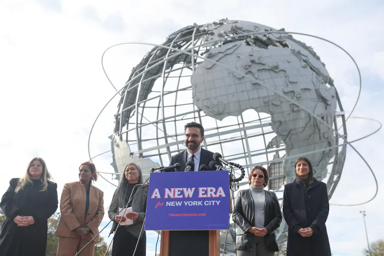 People in front of a spheric globe scuplture with a man behind a podium that says 'a new era.'