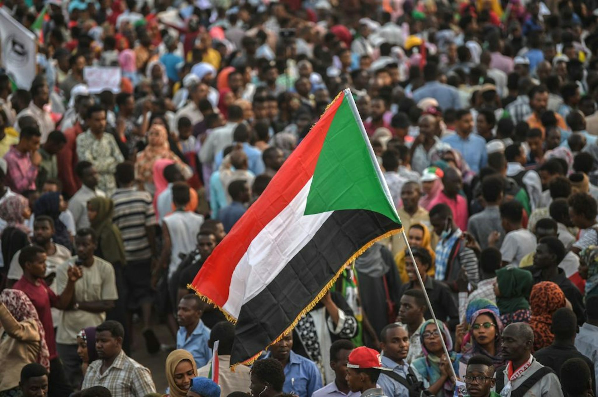 A crowd of people standing below a large flag
