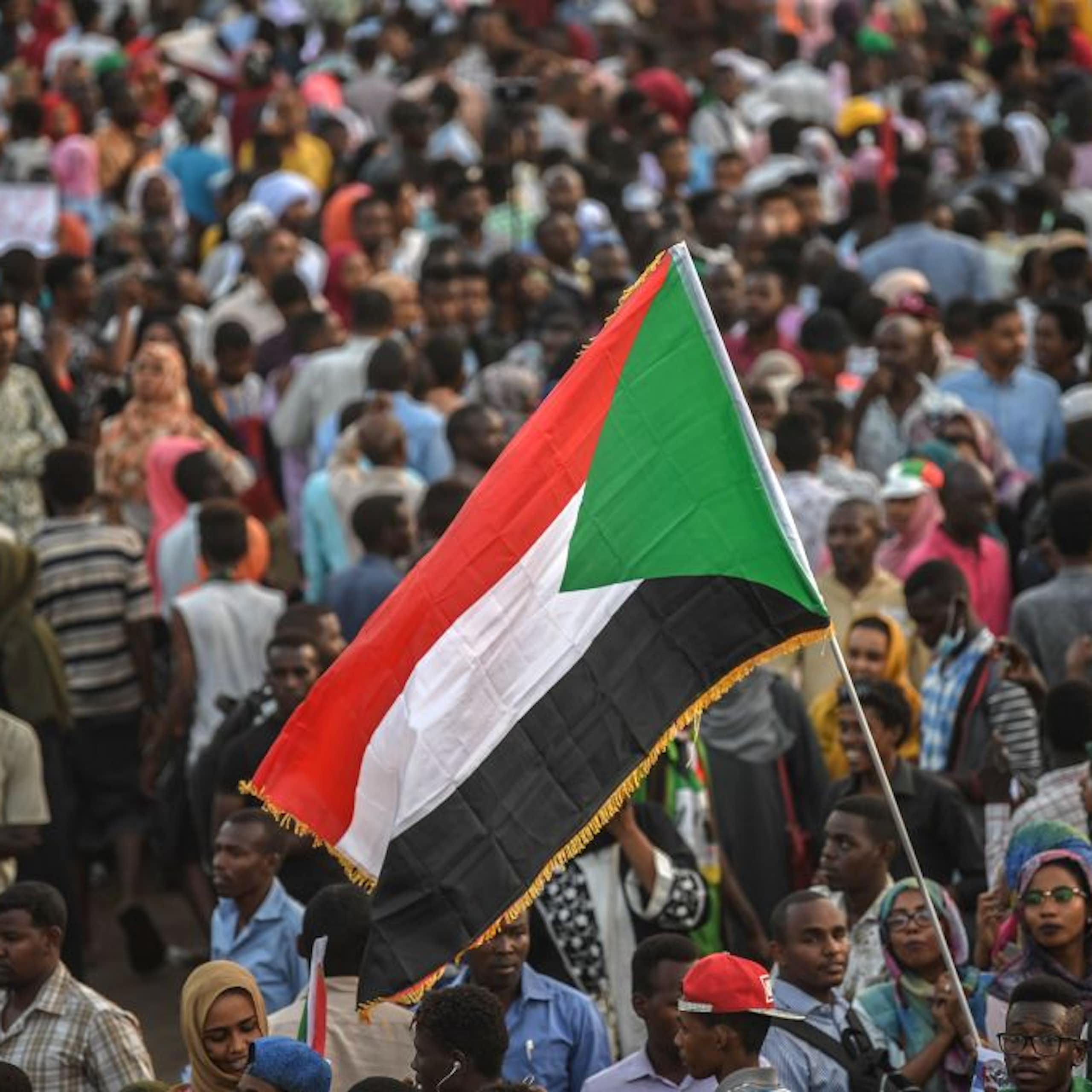 A crowd of people standing below a large flag