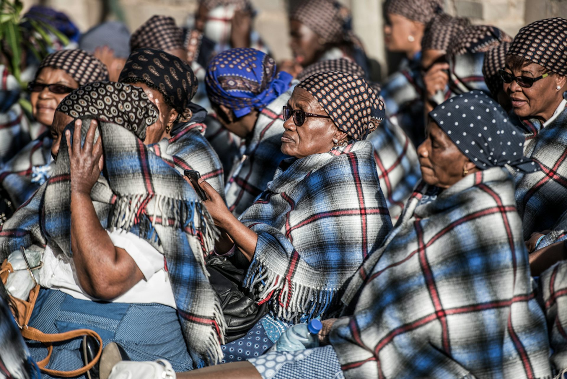 Group of women wearing chequered blankets and patterned headscarves