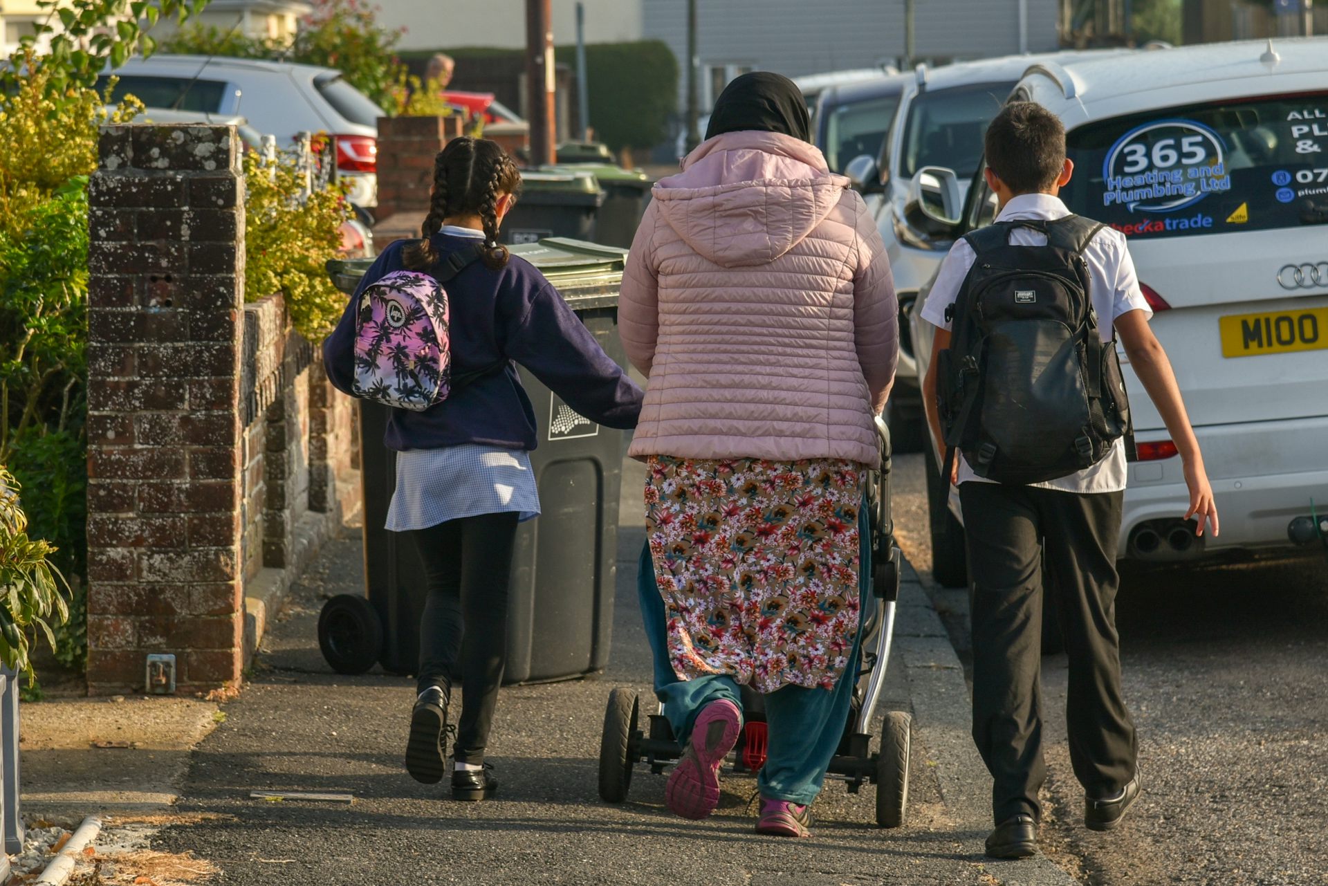 Woman walking down street with children.