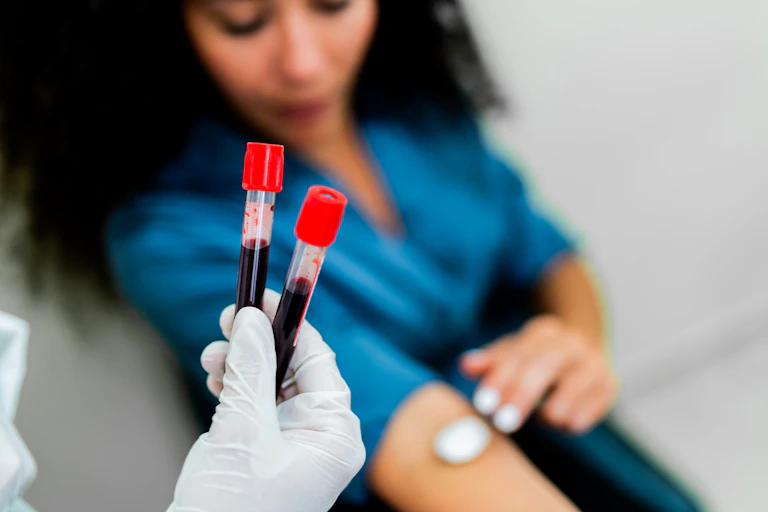 Health worker holding two tubes of blood, female patient sitting down