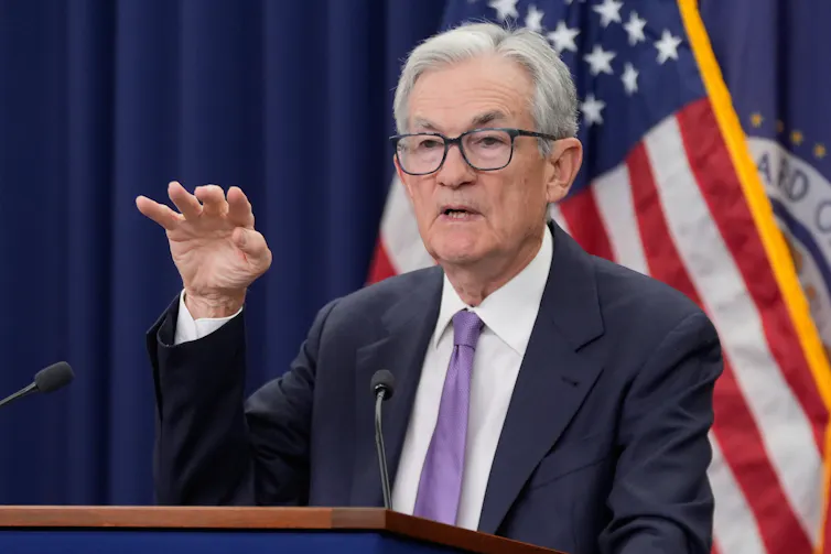 An older white man in a suit and glasses speaks from behind a podium