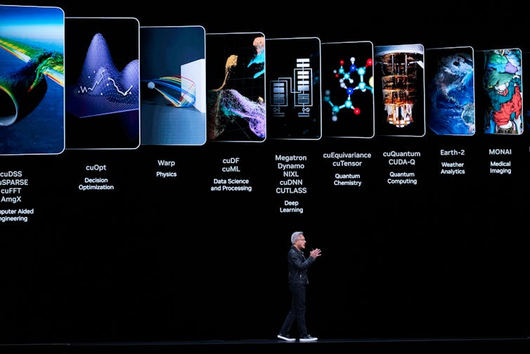 A man walks across a stage while a presentation on AI plays in the background