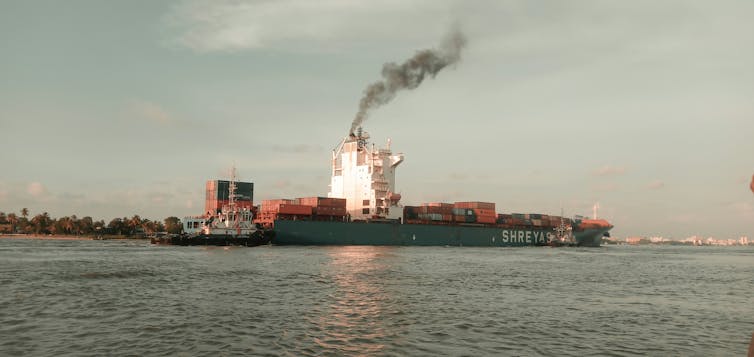 container ship with plume of smoke.