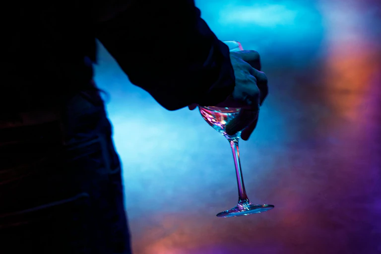 A man's hand holding a wine glass at a party