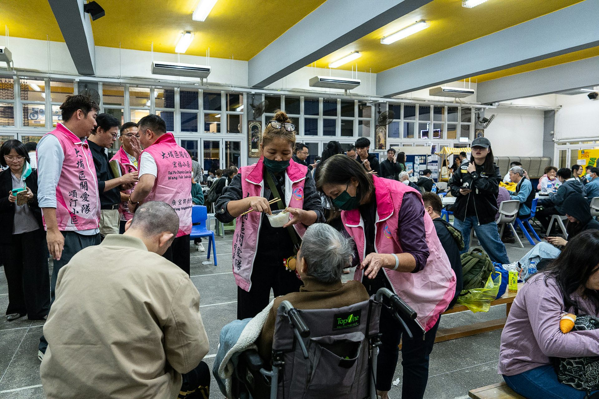 Officials in pink vests tend to elderly evacuated residents.
