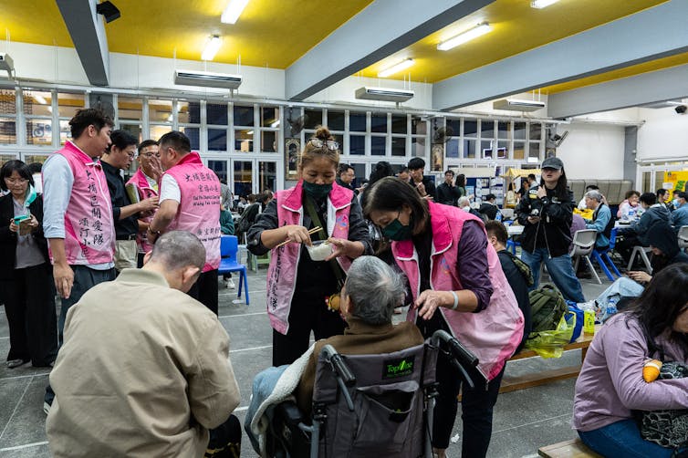 Officials in pink vests tend to elderly evacuated residents.