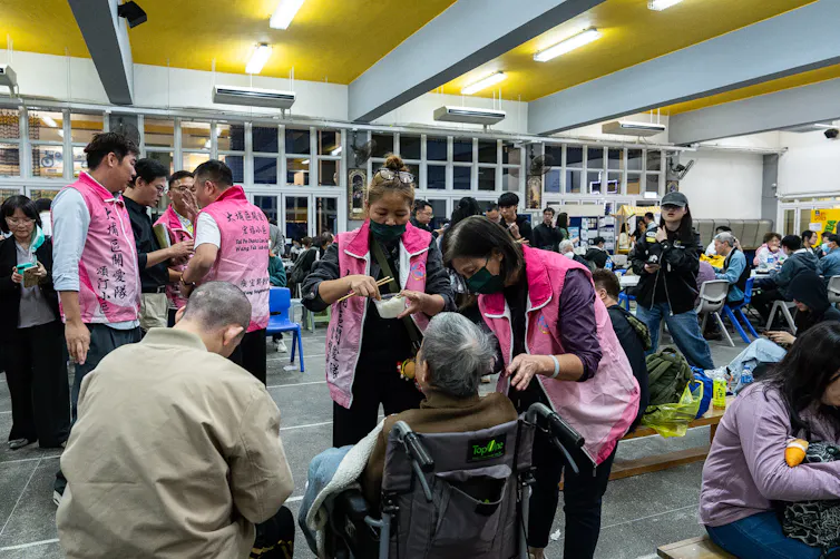 Officials in pink vests tend to elderly evacuated residents.