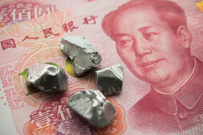 Pequeñas piedras grises sobre un billete rojo de yuan chino.