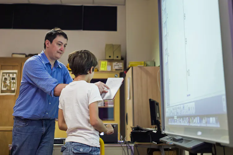 Un enseignement accompagne un élève dans sa lecture, en 2014, à Paris