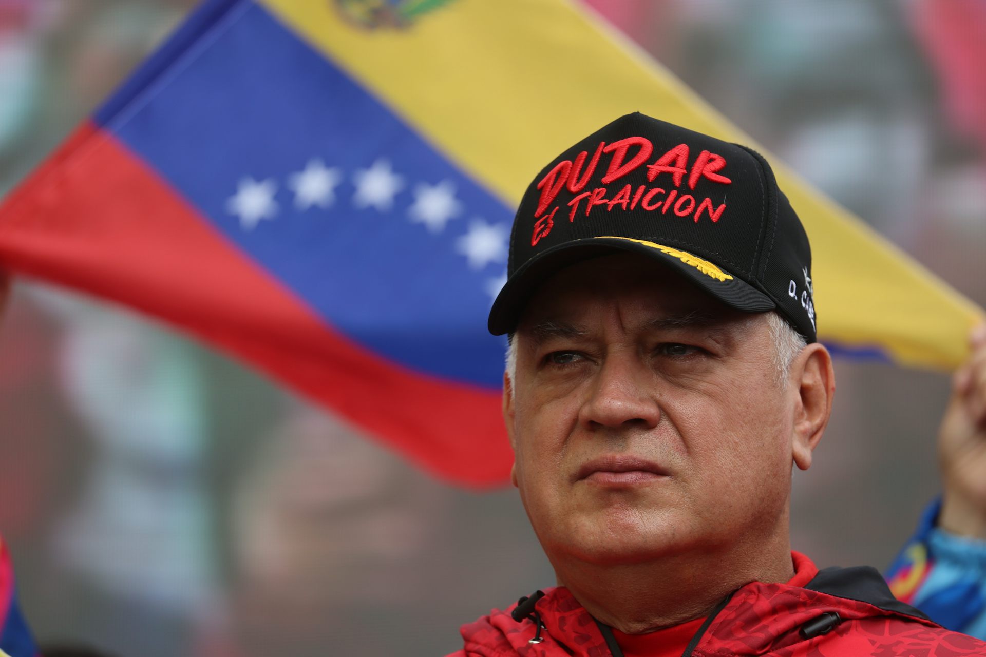 Diosdado Cabello wears a cap in front of a Venezuelan flag.