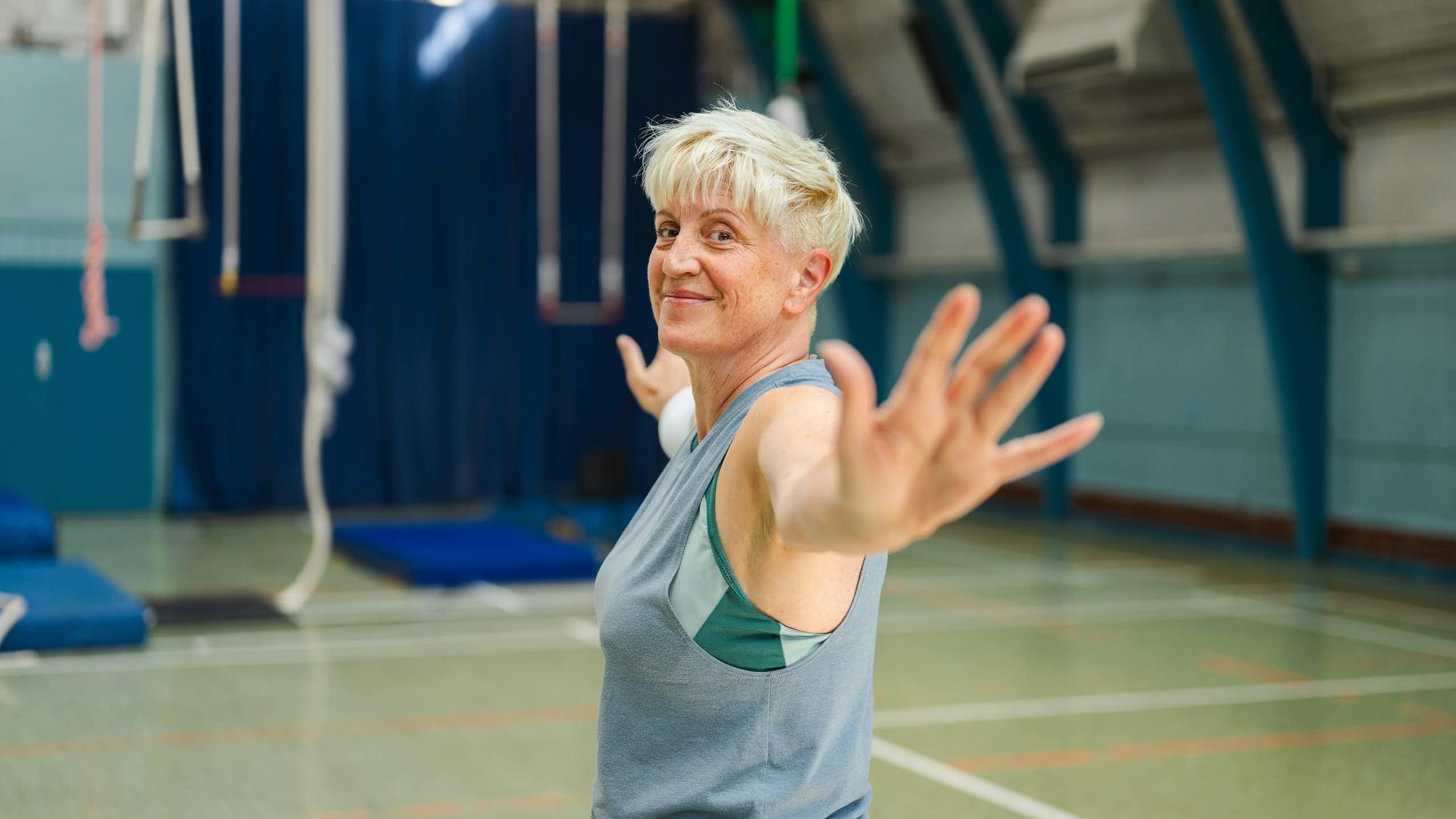 Une femme d'un certain âge fait des exercices d'étirement dans une salle de sport.