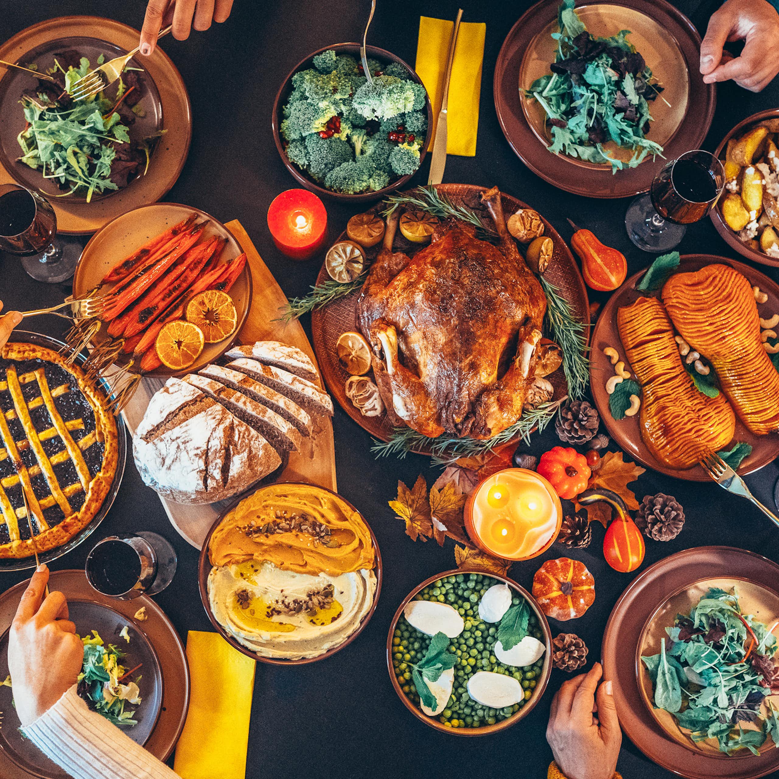Plan en plongée de personnes mangeant à une table chargée de nourriture, incluant une dinde et une tarte.