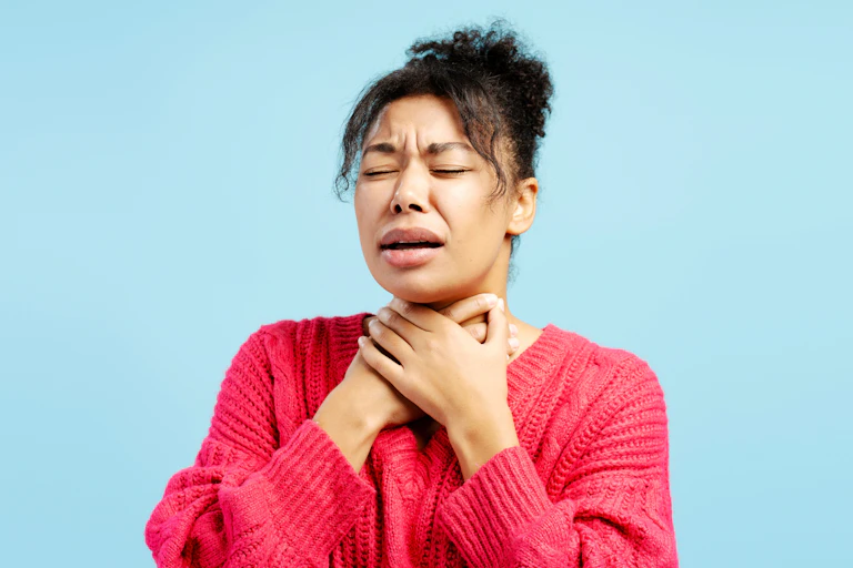 Woman holding hands to her throat