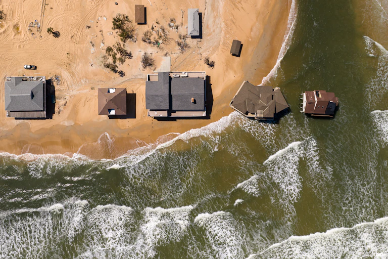 Casa sobre palafitas em uma praia bem perto da beira da água, e duas realmente dentro da água.