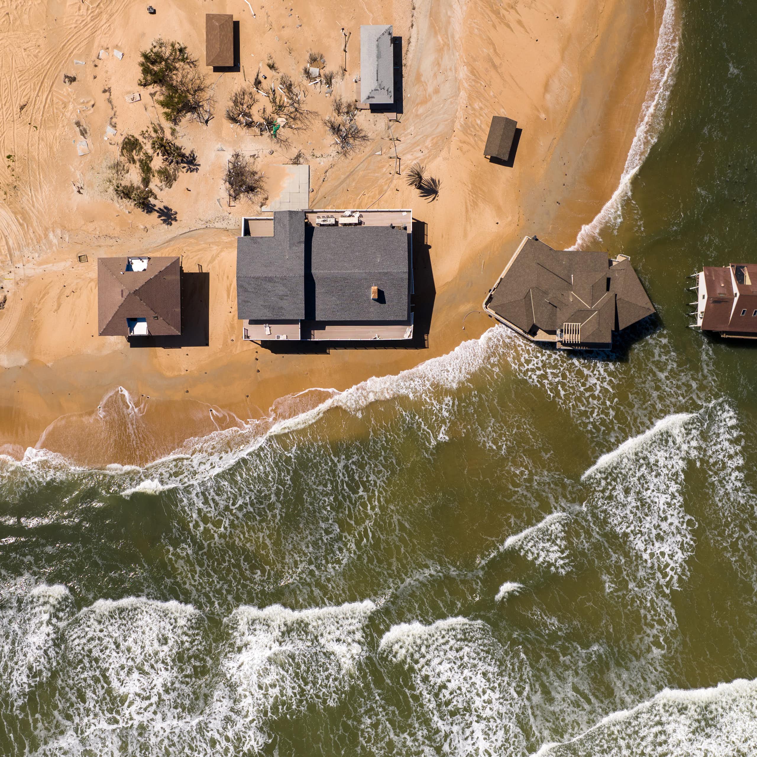 Casa sobre palafitas em uma praia bem perto da beira da água, e duas realmente dentro da água.