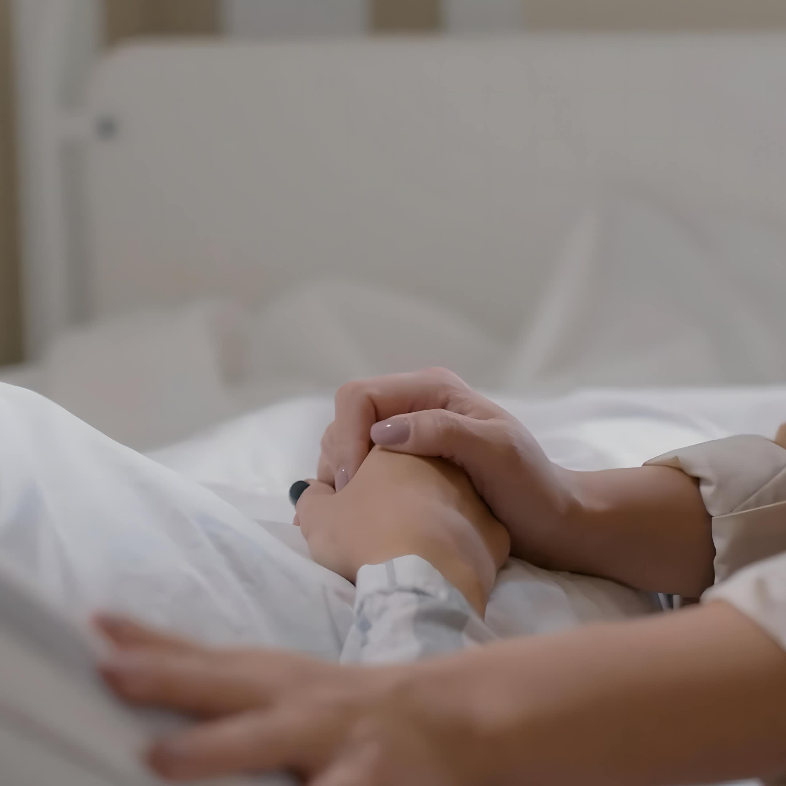 Una mano sujeta otra de un enfermo.