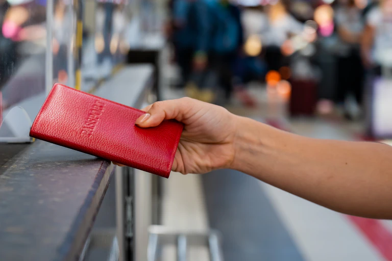 A hand handing over a passport in an airport at border control