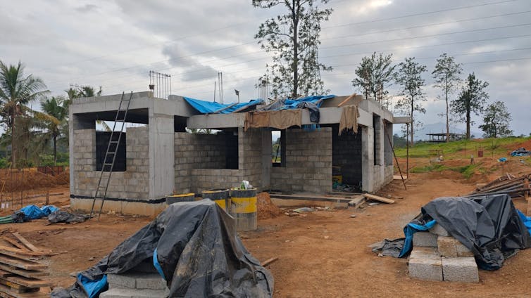 new house being built out of grey breeze blocks on land recovering from landslide