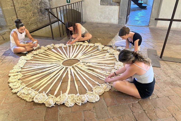 People sitting around a circular textile project.