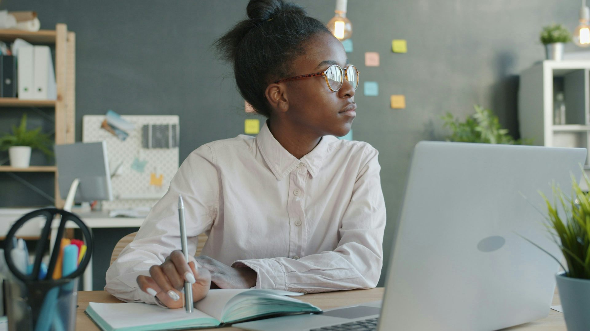 A young Black woman sitting in front of a laptop in an office