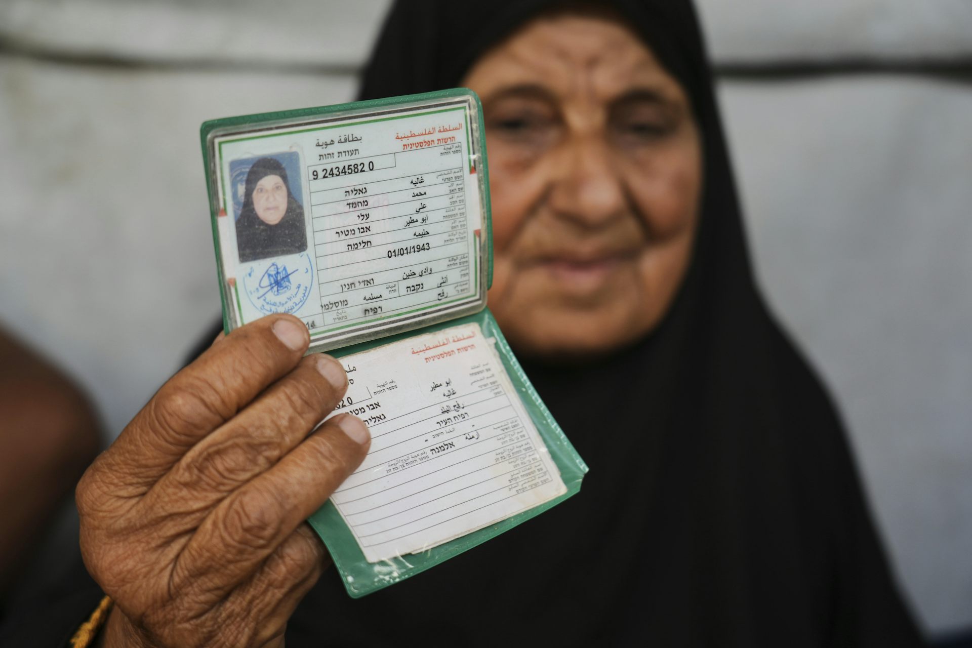 A veiled woman holds up an identification document.