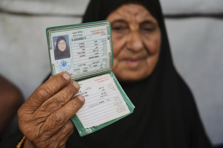 A veiled woman holds up an identification document.