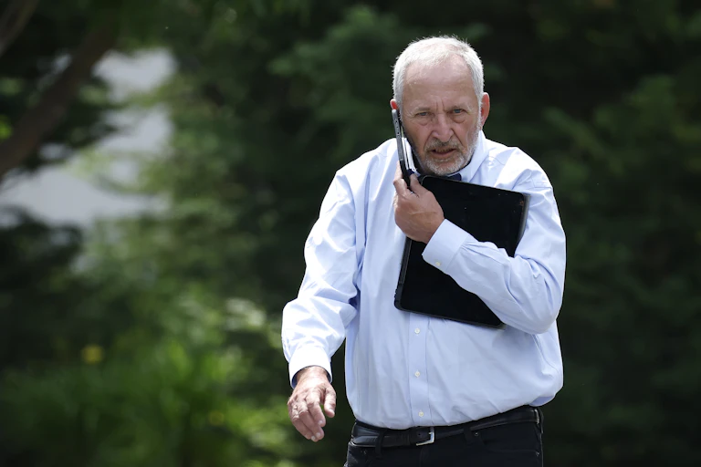 Larry Summers walks while talking into a mobile phone.