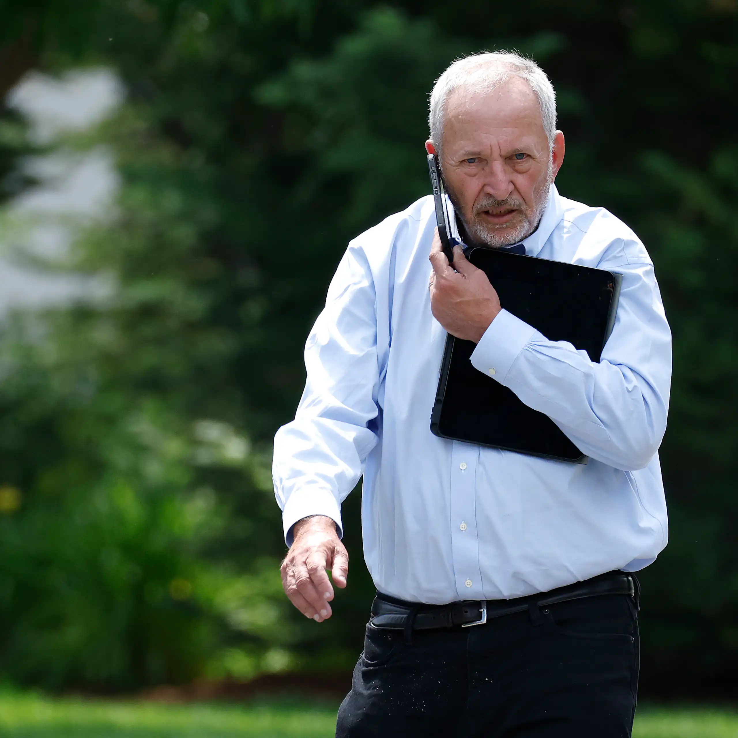 Larry Summers walks while talking into a mobile phone.