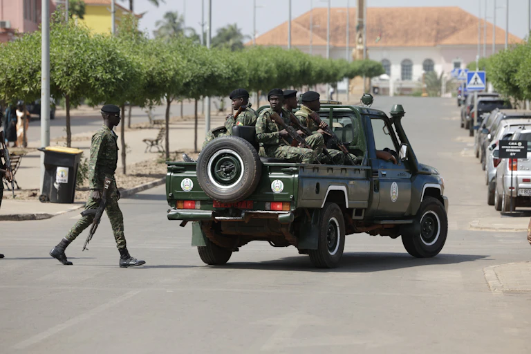 Men in an army jeep patrol a street.