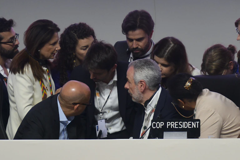 A group of negotiators stand around COP30 President Andre Correa do Lago