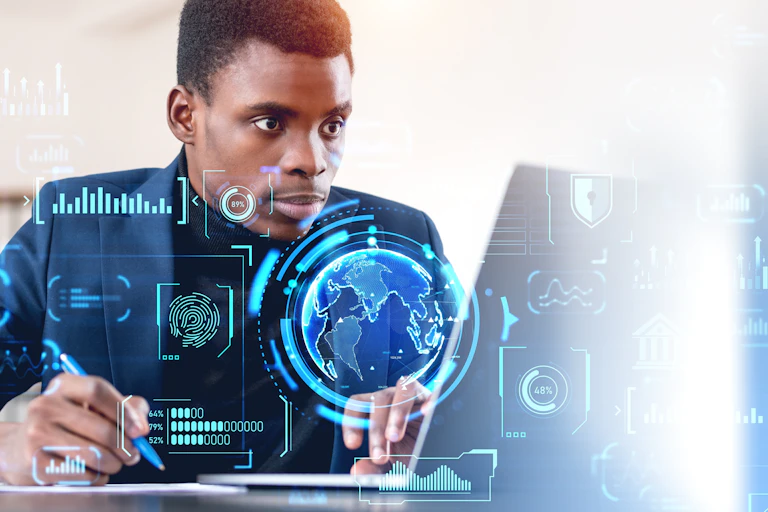 A man sits at a laptop while digital globes and graphs flash in the air around him, depicting his interaction with the digital economy