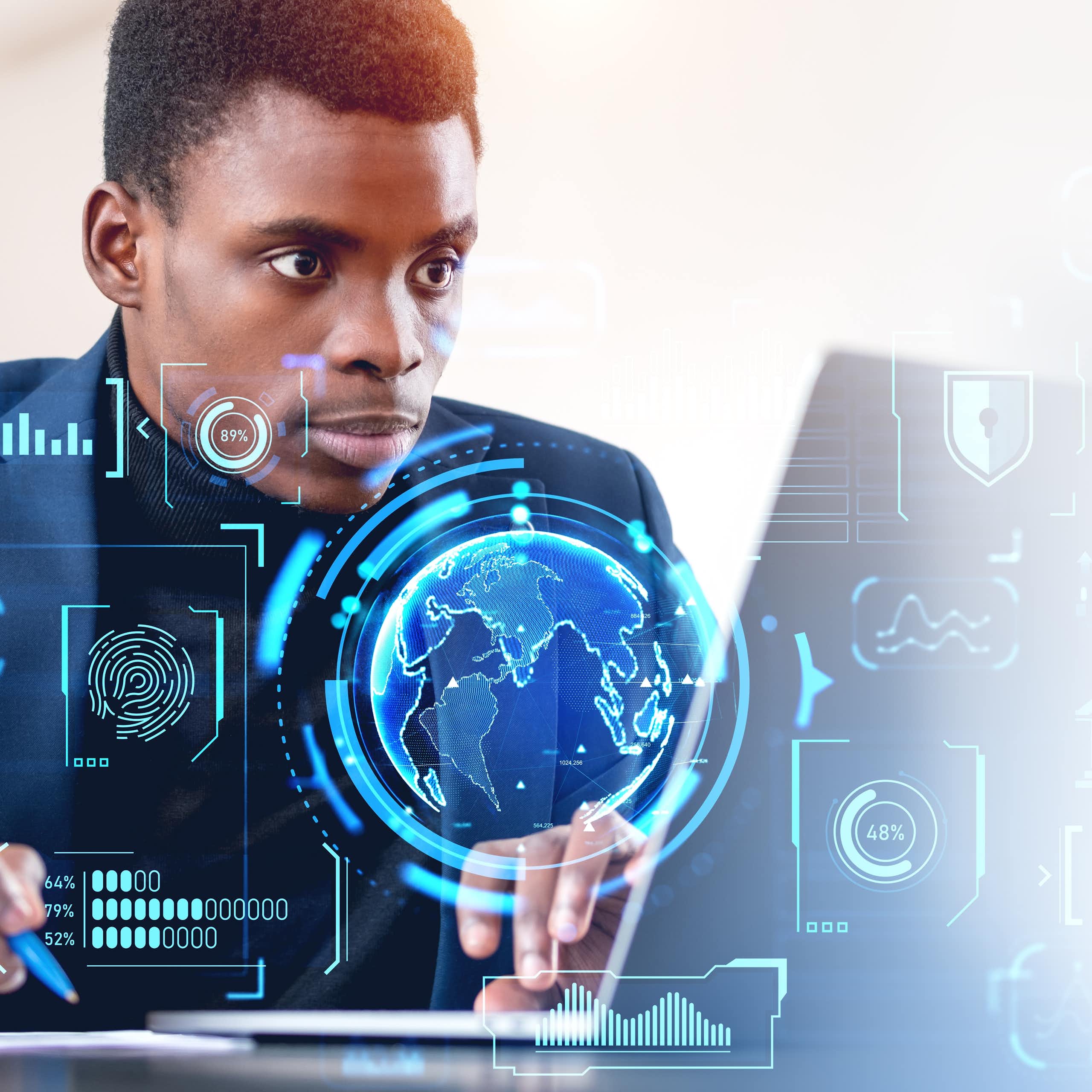 A man sits at a laptop while digital globes and graphs flash in the air around him, depicting his interaction with the digital economy