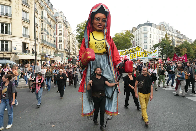 En tête de cortège, un participant porte une marionnette géante