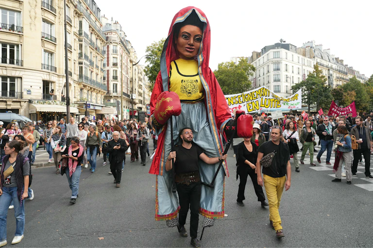 En tête de cortège, un participant porte une marionnette géante