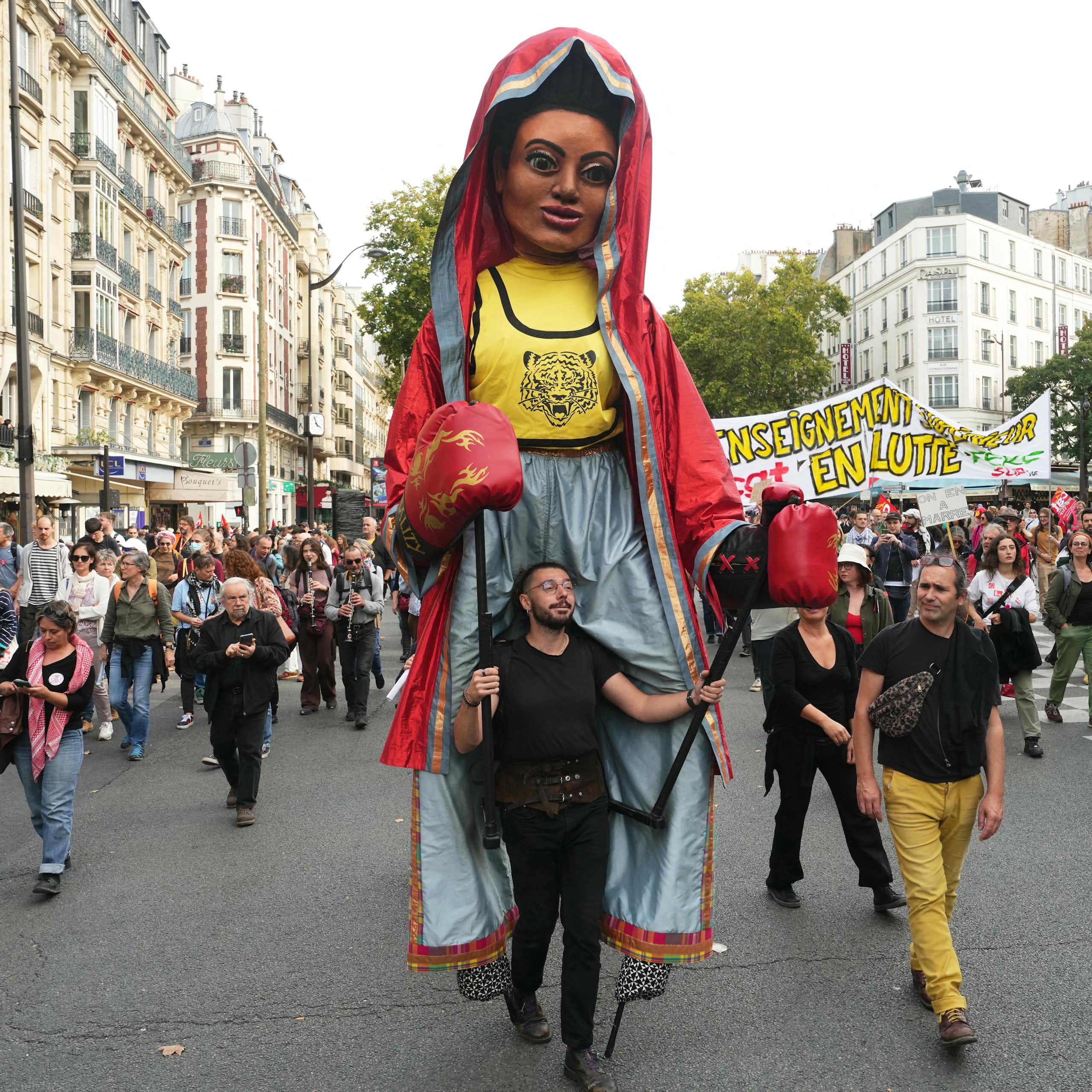 En tête de cortège, un participant porte une marionnette géante