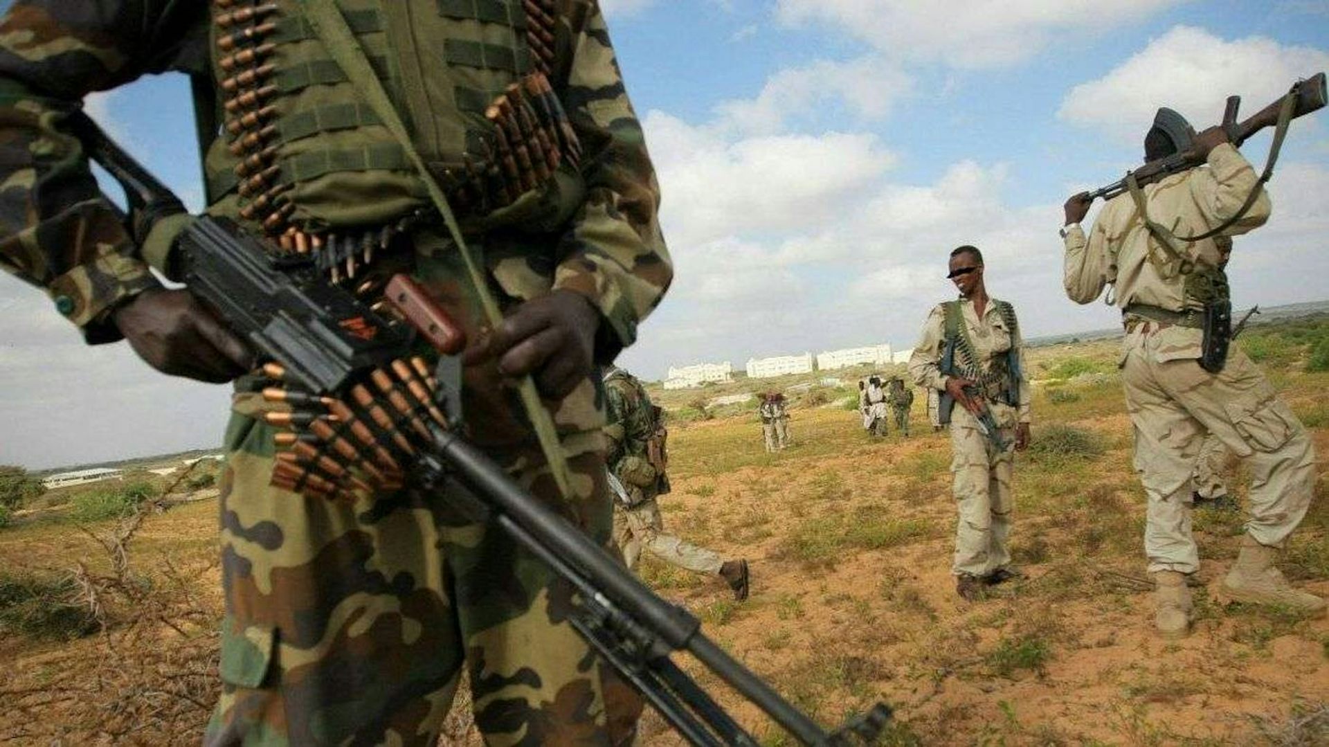 People in camouflage and khaki uniforms, carrying weapons