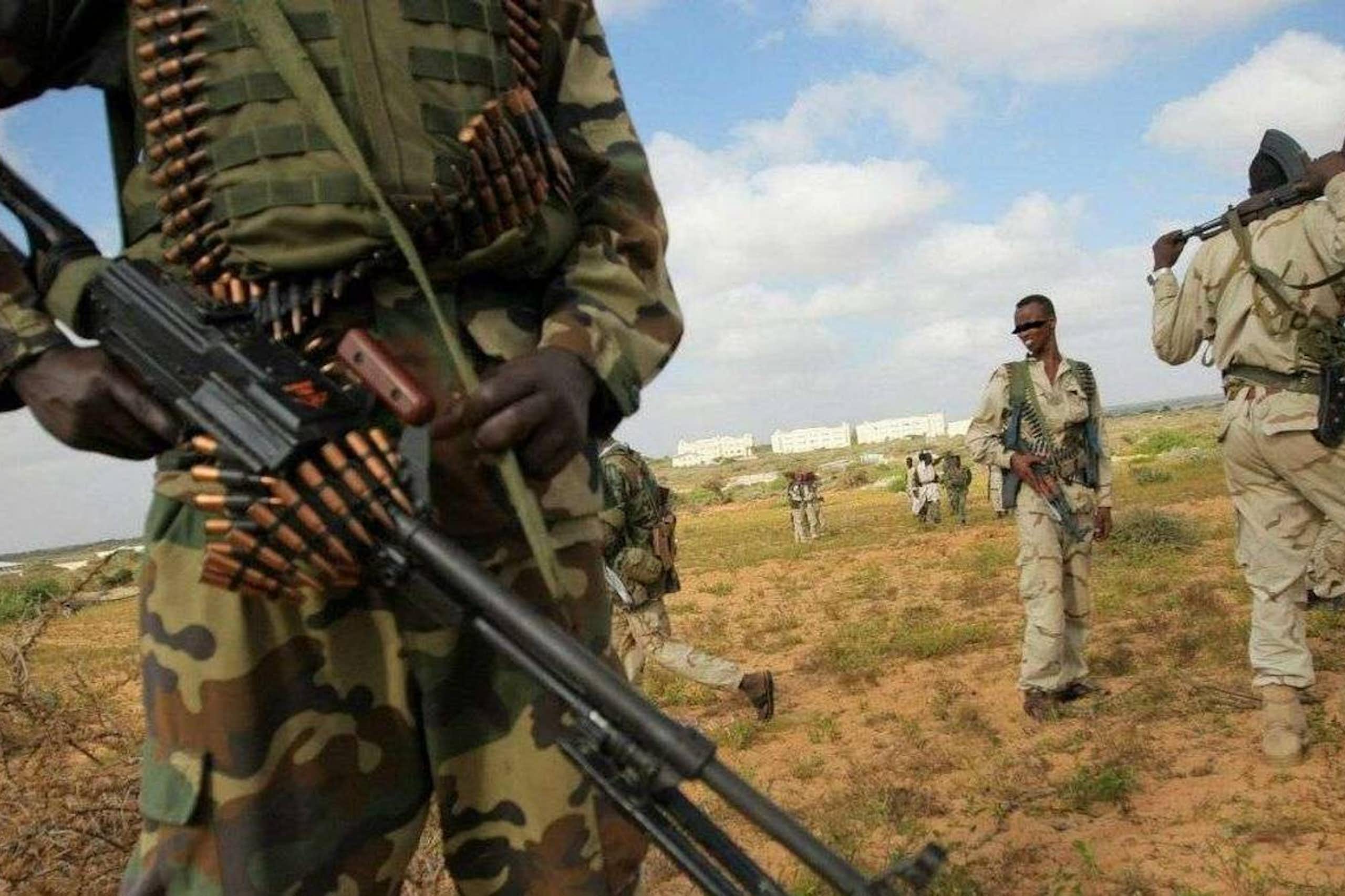 People in camouflage and khaki uniforms, carrying weapons